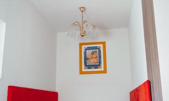 A small dining area with red upholstery and a table. A colorful picture is hanging on the wall.