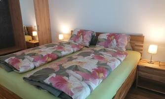 A cozy bedroom with a large bed and colorful blankets. Two nightstands with lamps provide gentle light.