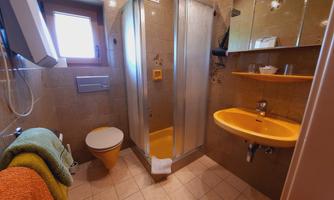 A modern bathroom with a shower cubicle and yellow sanitary fixtures. Towels in various colors are readily available.