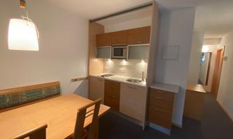 A modern kitchenette with a dining table and chairs. The room has a bright, welcoming atmosphere.