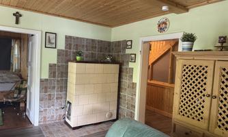 A cozy living space with a tiled stove and wood walls. In the background, two doors lead to other rooms and there is a rustic decor visible.