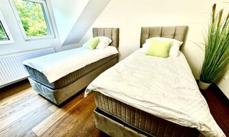A bright bedroom with two single beds and fresh duvets.  
Large windows provide plenty of natural light and a cozy atmosphere.