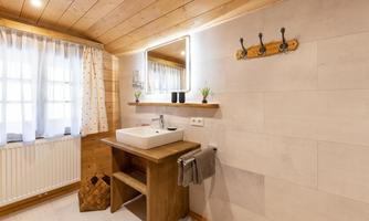 A modern bathroom with wooden paneling and a stylish sink faucet. The warm colors and natural light create an inviting atmosphere.
