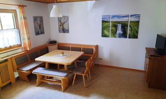 A cozy living space with an edible wooden dining nook. Pictures of nature hang on the wall, and there is a television in the corner.