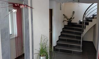 A modern entrance area with a tasteful staircase. On the left, decorative curtains hang and a plant gives the room a green accent.