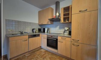 A modern kitchen with wood cabinets and a stove. The countertop is equipped with stainless steel appliances, and there is a bright, inviting atmosphere.