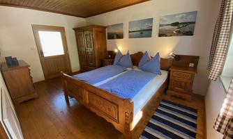 A cozy bedroom with a double bed and wooden cabinets. Pictures with landscape motifs hang on the walls.