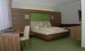 A modern hotel room with a large bed and a cozy seating area. The room is decorated in calm colors and has carpet flooring.