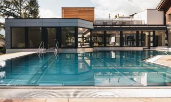 A modern pool in an elegant building. Surrounded by large windows and a clear sky.