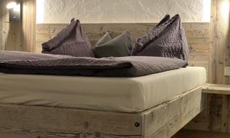 A modern bedroom with a comfortable bed and decorative pillows. The walls are made of wood, creating a cozy atmosphere.