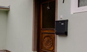 A front door with a decorative wood design and a mailbox. Plants in pots stand in front of the door.