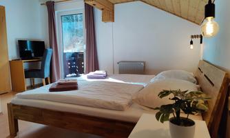 A cozy bedroom with a large bed and wooden furniture. The room has a window with a view outside and a small office.