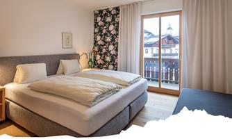 A modern bedroom with a double bed and a beautiful flower wall.  
Large windows provide plenty of natural light and a view of the surroundings.