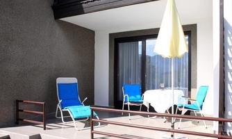 A cozy balcony with two blue loungers and a table. A parasol provides shade and invites relaxation.