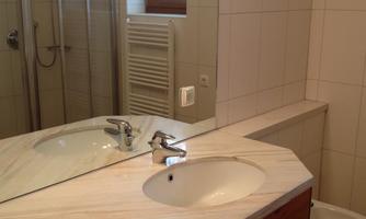 A modern bathroom with a shower and a large mirror. The vanity has two sinks made of marble and wood.