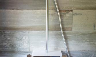 A modern shower system with a hand shower. The wall is designed in soft wood tones.
