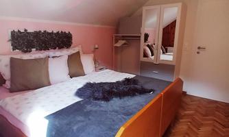 A cozy bedroom with a large bed and modern furniture. The walls are painted in soft colors, and the room feels bright and inviting.