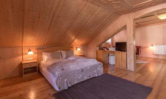 A cozy bedroom with wooden paneling and a large bed. The room is bright and inviting, with modern furniture and a flat-screen TV.