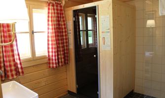 A modern bathroom with a shower and wood paneling. Red patterned curtains complement the cozy atmosphere.