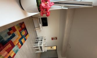 Here you can see the dining area with a table and chairs, as well as the living area with a TV. The generous windows provide light in the apartment all day long.
