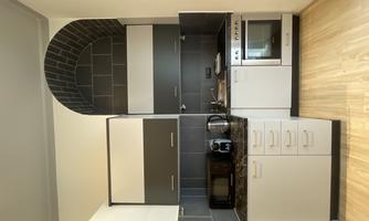 A modern kitchen with gray and white cabinets. It features kitchen appliances such as a stove, a refrigerator, and a microwave.
