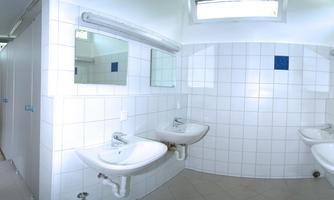 A clean bathroom with multiple sinks and mirrors. There are changing rooms and plenty of daylight.