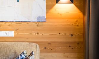 A cozy living area with wood paneling. A modern artwork hangs on the wall and a stylish wall lamp illuminates the space.