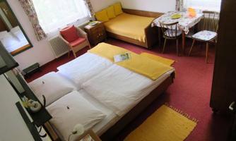 A cozy room with a double bed and a single bed. There is a small table with chairs and plenty of daylight through the windows.
