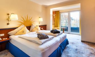 A cozy bedroom with a double bed and warm colors. There is a balcony with a view outside and a pleasant atmosphere.