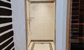 A bright shower with tiled walls and a modern showerhead. The floor is decorated with a heart-patterned rug.