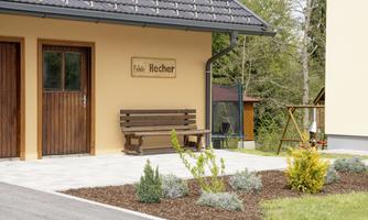 A cozy holiday home with a wooden bench in front of the entrance door. The surroundings are green and well-maintained, perfect for outdoor relaxation.