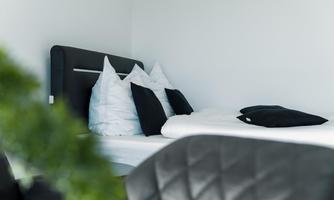 A modern bedroom with a comfortable bed and several pillows. The room is bright and designed in a minimalist style.