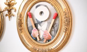 An artistic painting in a golden frame displays a person with a toilet paper roll face. In their hands, they hold large, red matches.