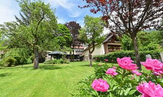 A beautiful garden with colorful flowers and green trees. In the background, a cozy house can be seen.