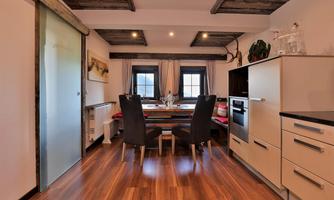A modern kitchen with a dining area. Bright colors and wooden details create a cozy atmosphere.