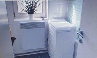 A small room with a washing machine and a radiator. There is a plant on the windowsill.