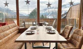 A cozy dining area with a large table and atmospheric decoration. A view of the mountains and nature through the windows.