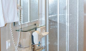 A modern bathroom with a sink and a shower cubicle. The walls are brightly tiled, and the space feels clean and inviting.