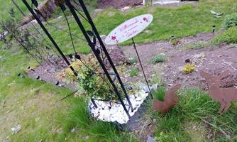 A pretty garden path with a welcome sign and decorative elements. On the left side, plants and small figures can be seen.