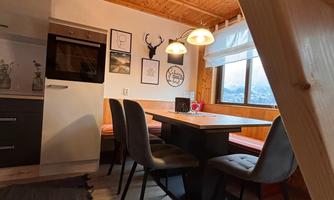 A cozy kitchen with a wooden ceiling and modern dining area. The room has windows with a view outside and is stylishly decorated.
