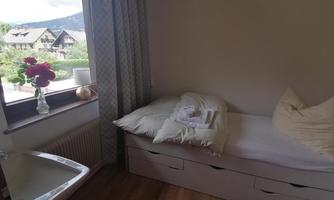 A simple bedroom with a single bed and a windowsill. The room is bright and has a beautiful view of the countryside.