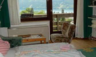 A cozy room with a view of a lake. Large windows let in plenty of light, and the furniture is simple and inviting.