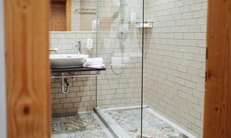 A modern bathroom with a shower and a sink. The floor has a decorative pattern and the walls are tiled with bright tiles.