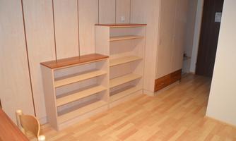 A simple room with wooden shelves and a bright floor. The walls are kept light, and the room appears friendly and spacious.