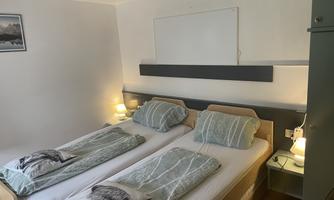 A bright room with two separate beds and soft colors. There are nightstands with lamps and a calm atmosphere.