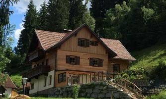 A charming wooden house surrounded by trees and meadows. The architecture is traditional and inviting.