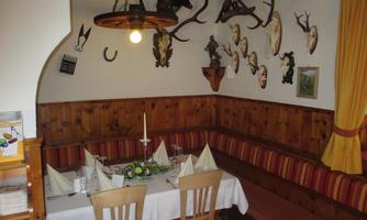 A cozy restaurant with wooden paneling and a festively laid table. Hunting trophies and decorative elements hang on the walls.