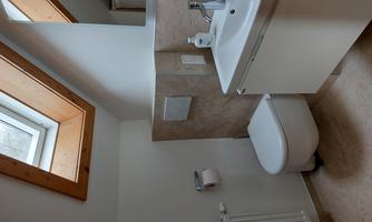 A modern bathroom with a skylight and a sink. The walls are light and appear friendly.