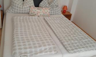 A modern double bed with checkered bedspreads and pillows. The room is bright and comfortably furnished.