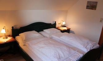 A cozy bedroom with a large double bed and bedside tables. Soft light from the lamps creates an inviting atmosphere.